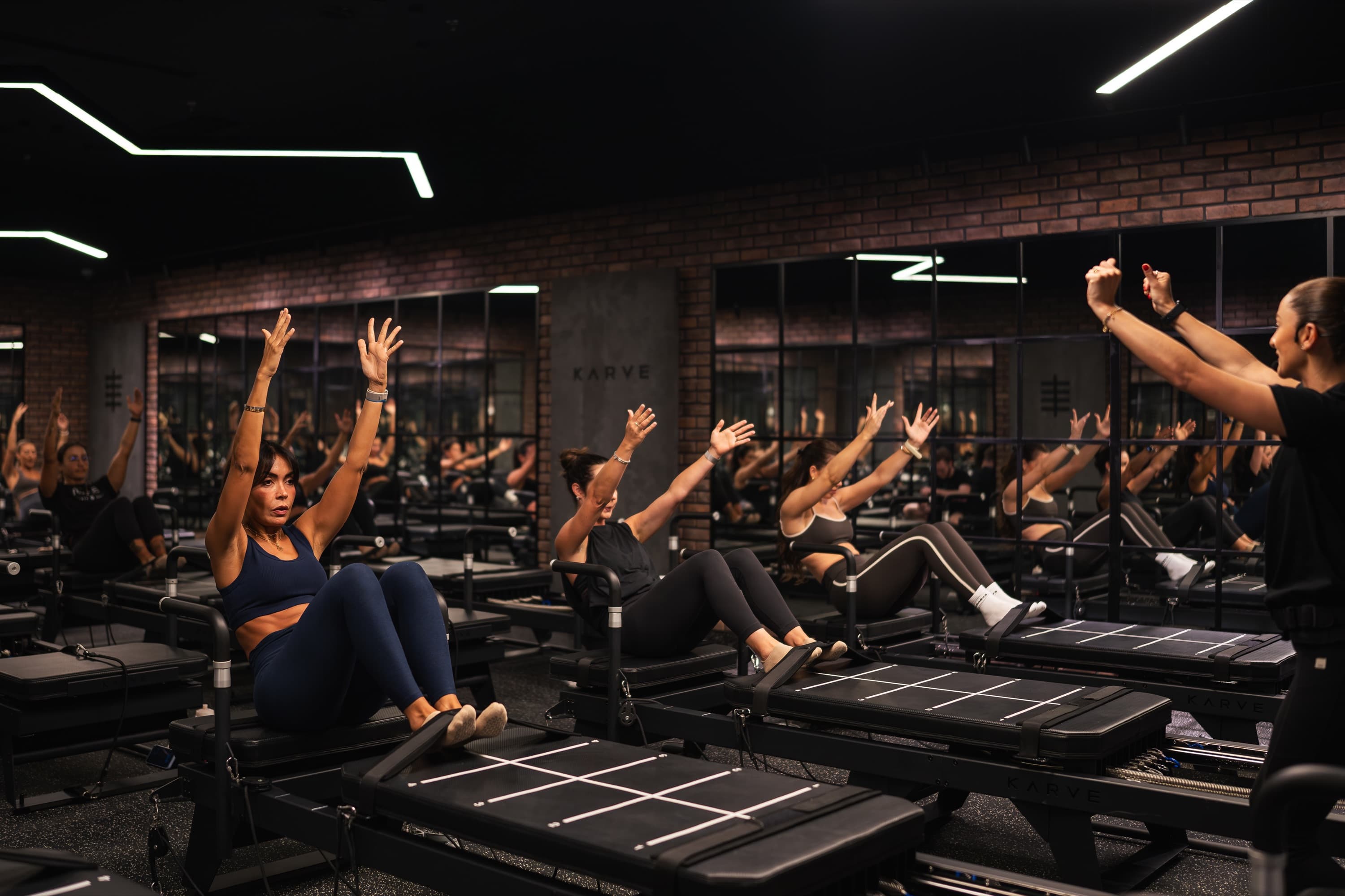 A KARVE Transformer Pilates class A full KARVE class mid-exercise on Transformer machines, instructor coaching from the front